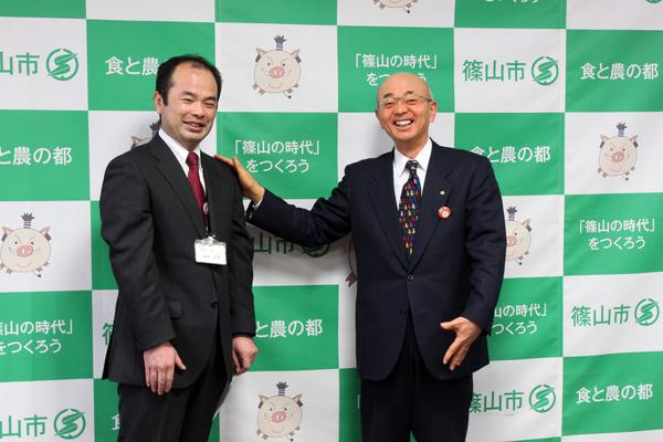 市長が酒井 正幸さんの肩に手を載せて激励している様子の写真
