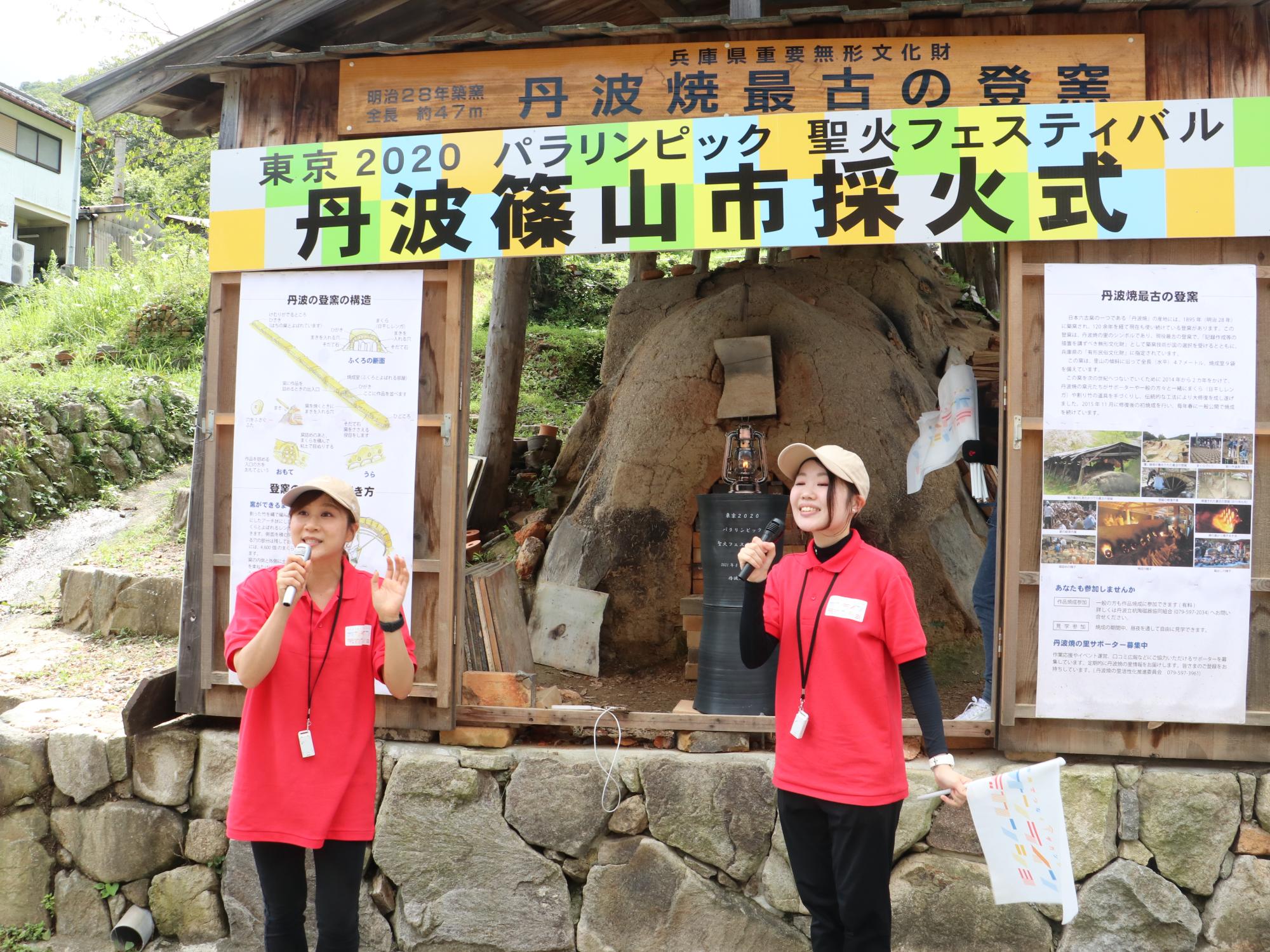 聖火の採火式が行われた最古の登り窯の前で女性リポーター2人が話している。