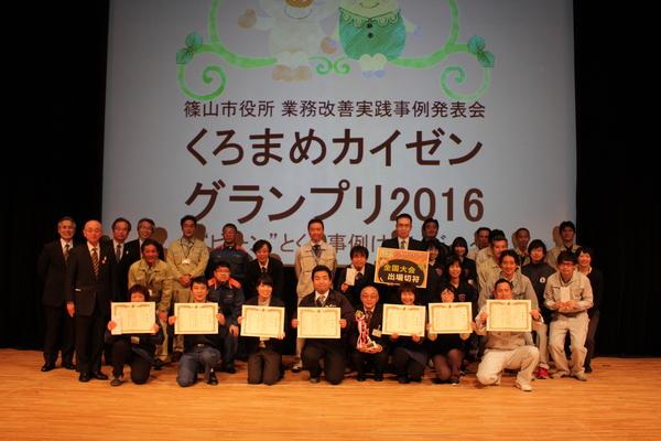 壇上にてくろまめカイゼングランプリ入賞チームが賞状を持って記念撮影