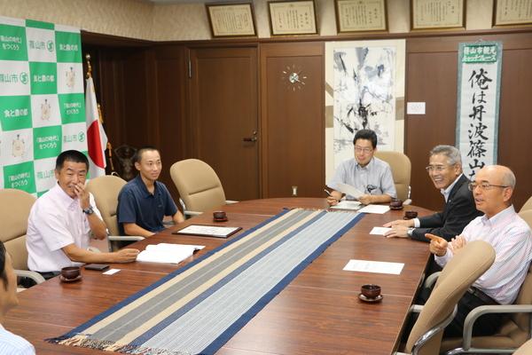 市長と教育長の前に顧問の森本先生と清水君が座っており、談笑している様子の写真