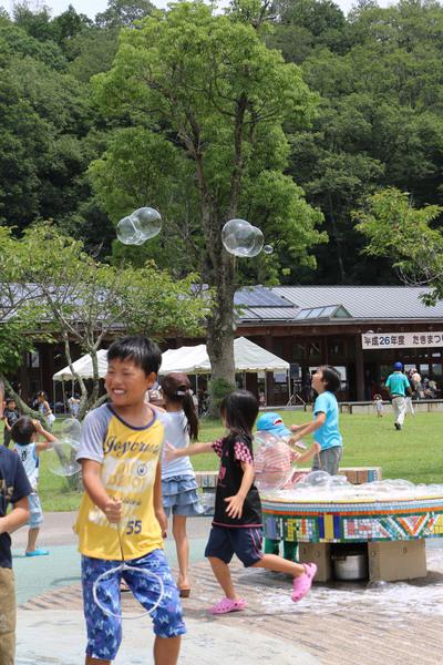 子供たちが遊んでいる頭上にシャボン玉が飛んでいる写真