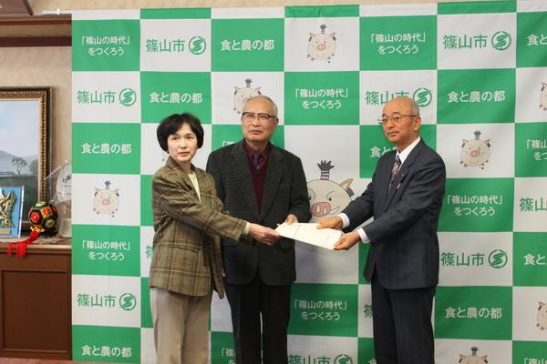 新家 龍委員長から「篠山市住民投票条例（仮称）検討委員会報告書」の提出を受け取っている市長の写真