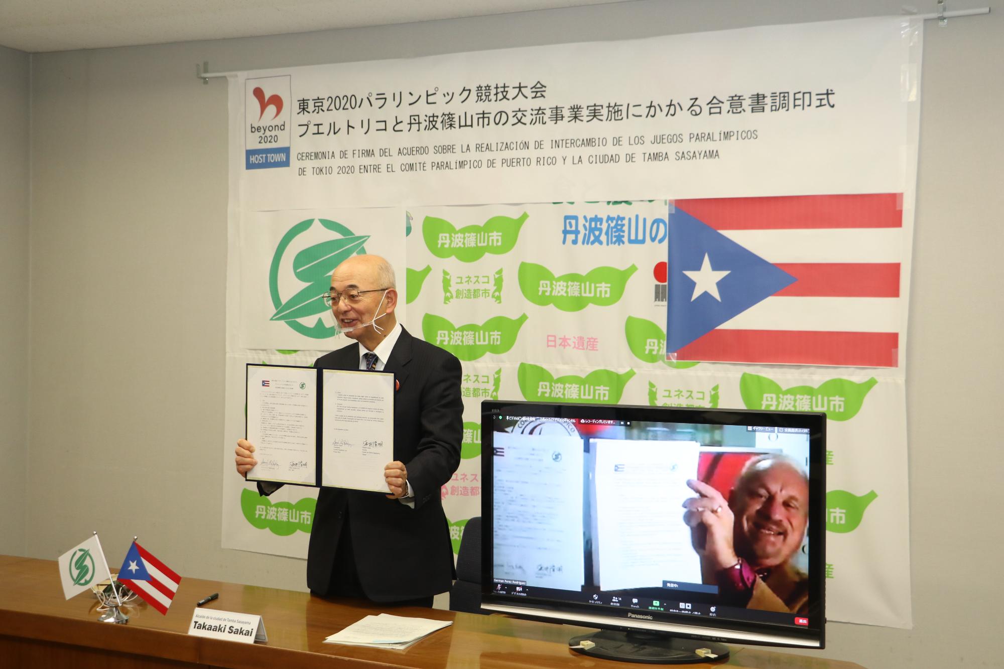 オンラインでの調印式。酒井市長と、プエルトリコの方が画面越しに調印書を見せ合っている