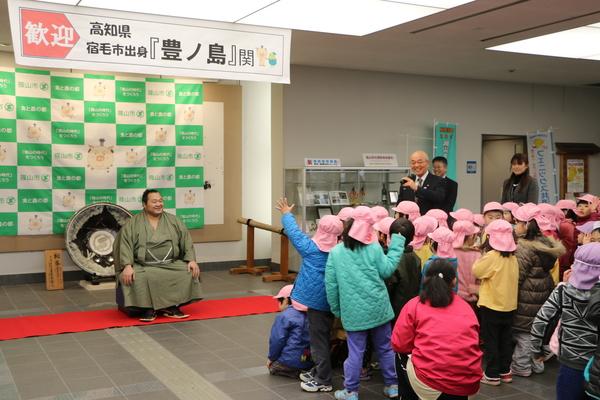 ピンクの帽子をかぶった子供たちの前に、座る豊ノ島関の写真