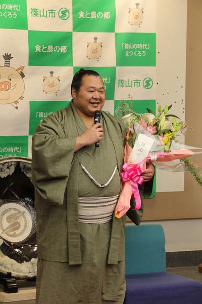 花束を持ち、笑顔でマイクをもって話す豊ノ島関の写真