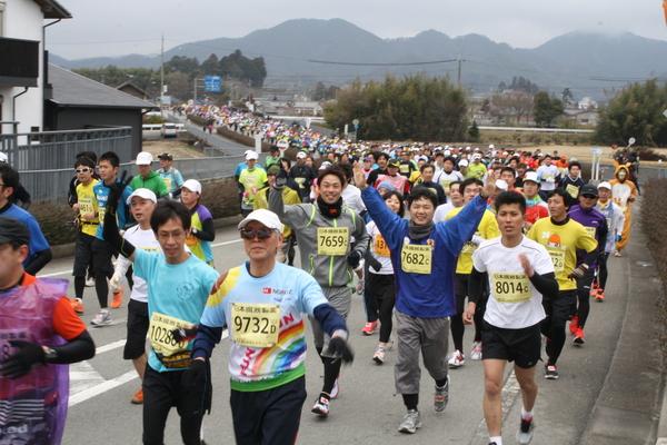 胸にゼッケンをつけた大勢の参加者たちがスタートしている写真