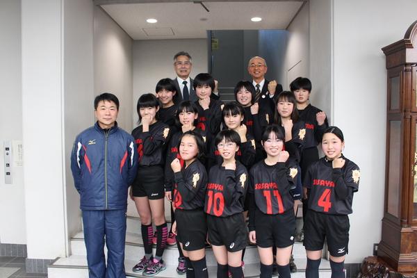 選抜で選ばれた12名の選手と、市長、教育長、関係者の男性が一緒にガッツポーズをして写っている写真