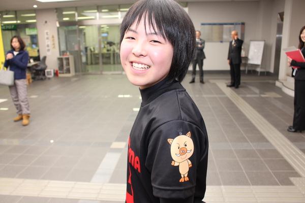 黒に赤字で「SASAYAMA］と書かれており、肩にまるいののイラストがプリントされたユニホームを着た女の子が笑顔で写っている写真