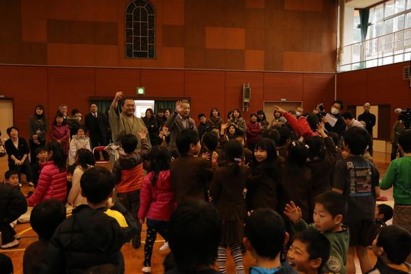 豊ノ島関の周りに集まる、沢山の小学生と片手を上げじゃんけんをしている写真
