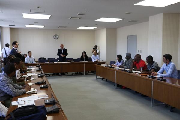 会議テーブルに座る、市長、関係者と、アフリカ、ミャンマー、インドネシア各国の農業技術職員の写真