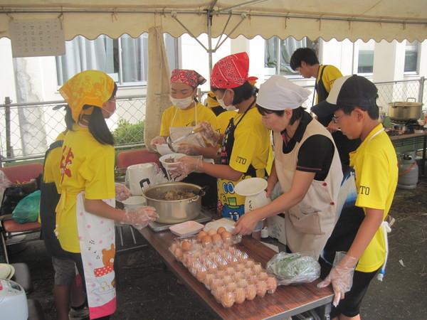 頭にバンダナや帽子を被ったエプロン姿の生徒たちが「じょうとうまるごと丼」を白の丼ぶりによそっている写真