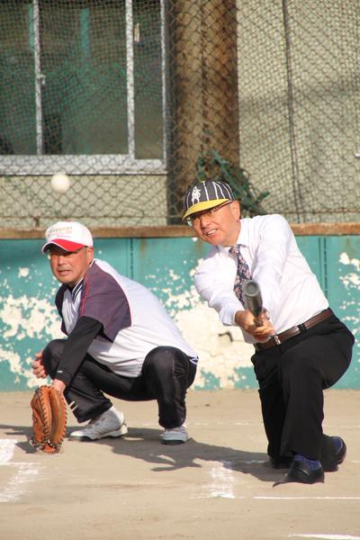 バットでボールを打ち返した市長とその後ろでキャッチャー役の男性がミットを構えている写真