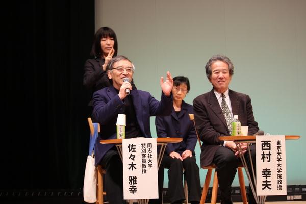 同志社大学の佐々木 雅幸教授が話をしている後ろで、女性が手話翻訳している写真