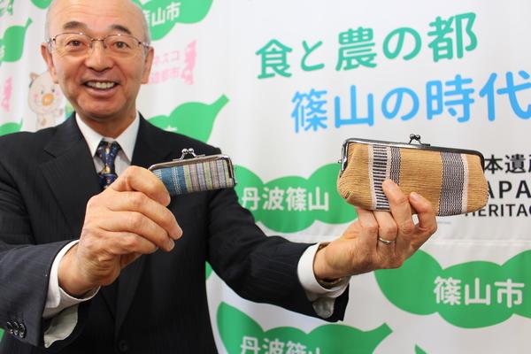がま口の小物入れを手に笑顔の市長の写真