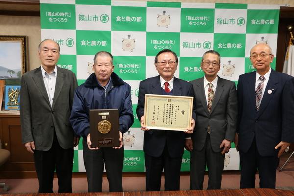 表彰状と盾を持った野々垣生産組合の人々と市長との記念写真