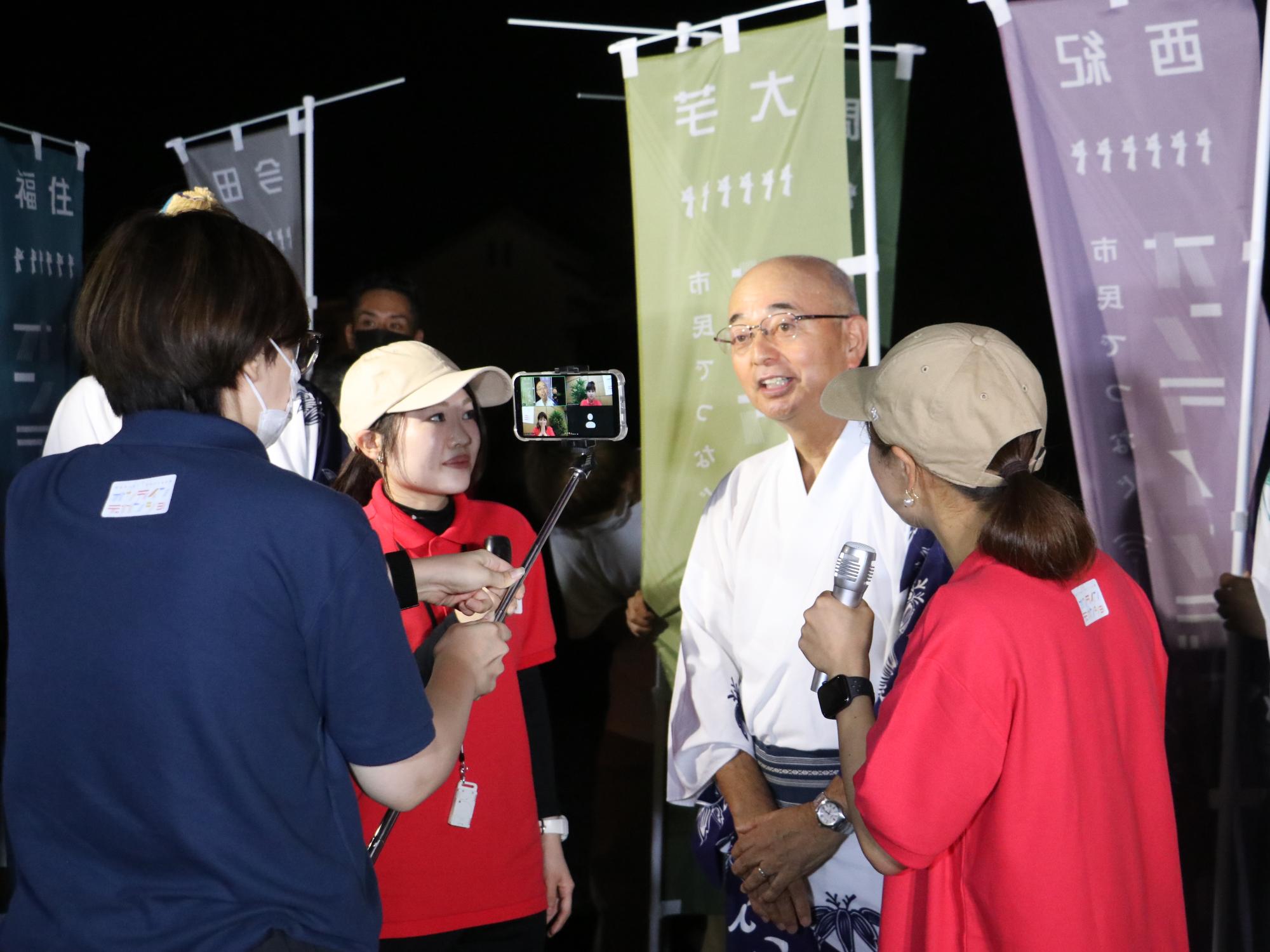 フィナーレで女性リポーター2名からインタビューを受けている市長