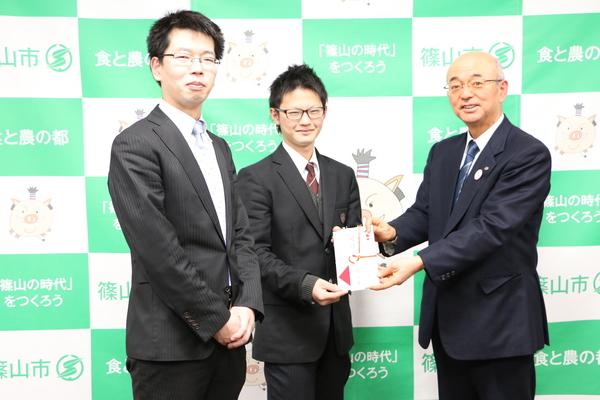 顧問の福田先生、森本くんに市長がのし袋を手渡している写真
