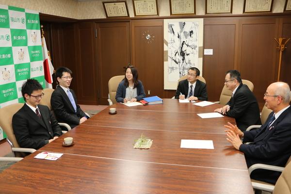 市長室の大きな円卓に表敬訪問に訪れた森本くんと顧問の福田先生が話をしているのを市長他職員3名も加わり笑顔で話しを聞いている写真