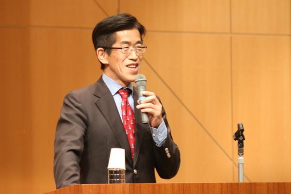 右手にマイクを持ち壇上で講演されている岸博幸さんの写真
