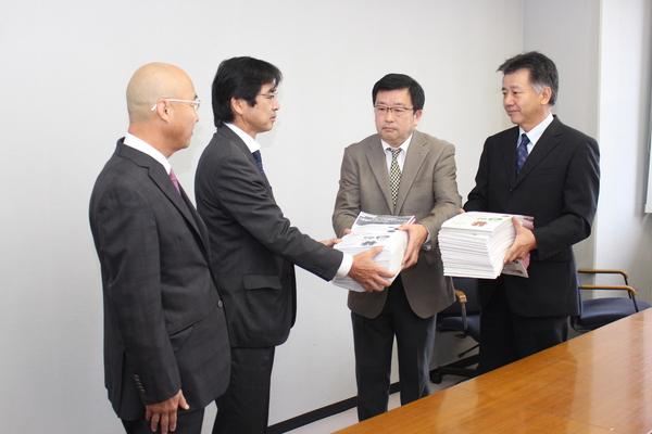 市長の横で、署名書類を市議会議長へ渡している写真