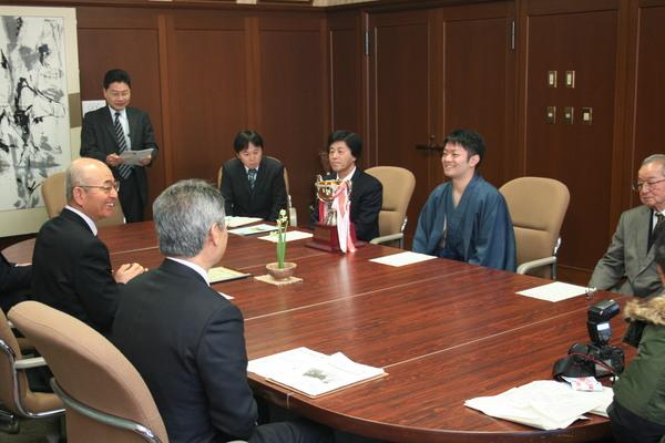 市長の前に、岸田 諭さんが座っており、笑顔で話をしてる様子の写真