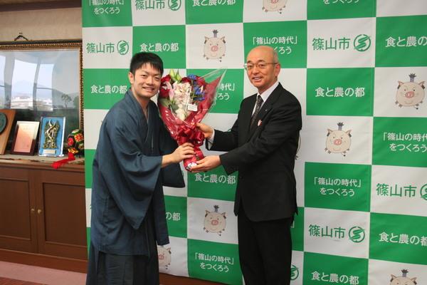 岸田 諭さんが市長から花束をもらっている様子の写真 拡大画像