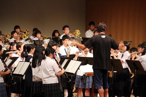 市内の中高生の前を指揮をする佐渡 裕さんの後ろ姿の写真