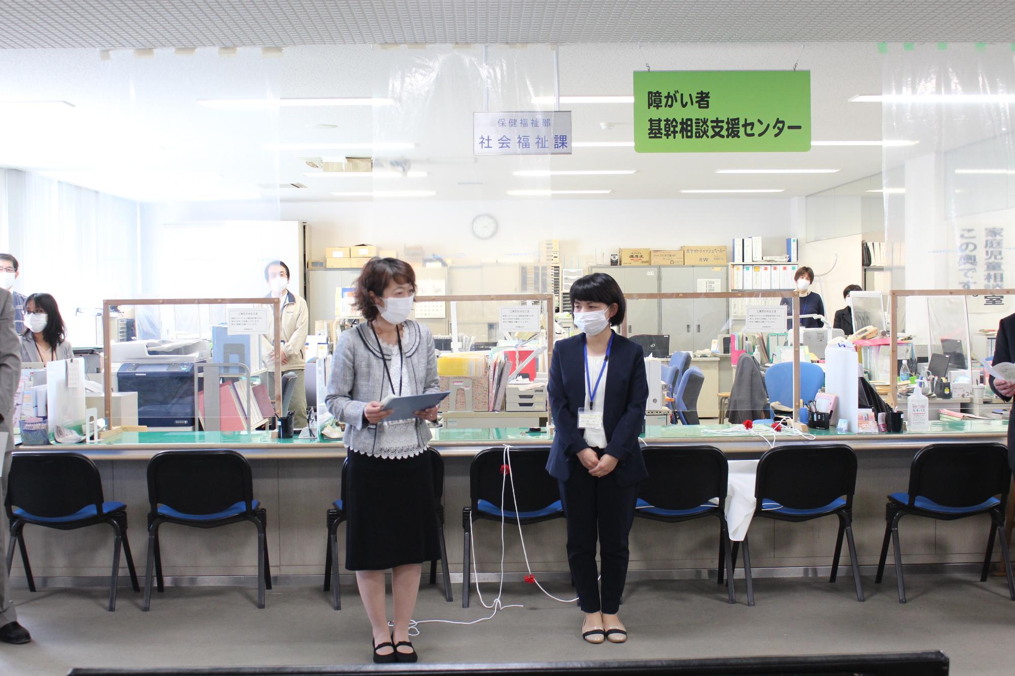 女性2人が式典に参加されている方を前にして挨拶している。