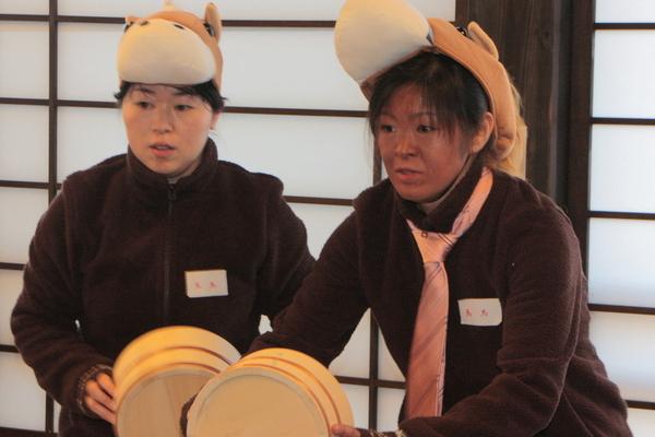 馬の被り物をした2名の女性が桶を持ち構えている写真