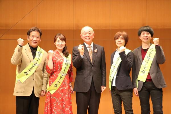 ふるさと大使4名が市長の両脇を挟んで一列に並び右手をグーにしてポーズをとっている集合写真