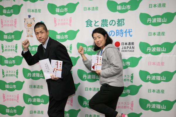 ランナーの西山 通夫さんと森田 明子さんが左手に目録を持ち右手でガッツポーズをしている写真