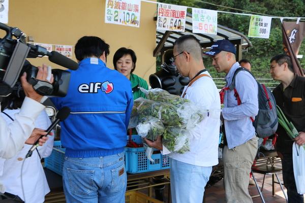 販売ブースにて男性が数袋の枝豆を持っている写真