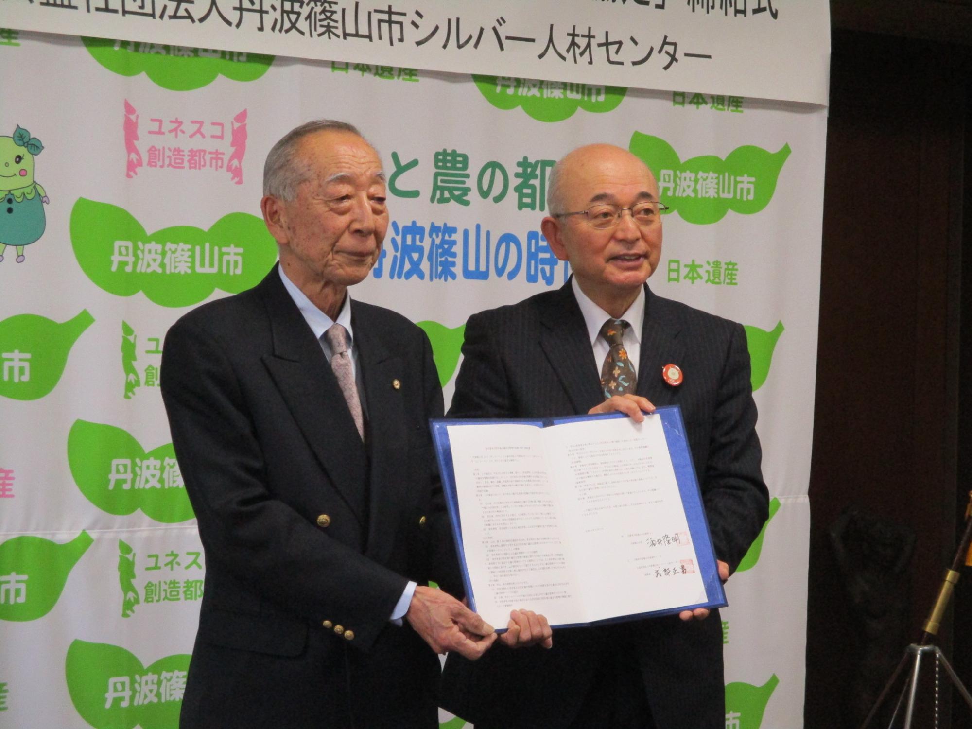 協定書を、市長とシルバー人材センター事務局長が一緒に持っている
