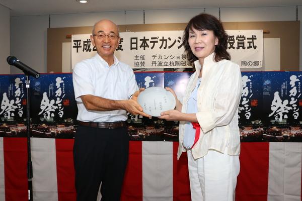 日本デカンショ節優秀賞の高橋さんと市長がお祝い品を持ち記念写真