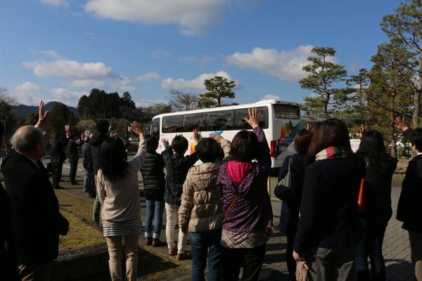 お母さんたちがバスに手を振っている後ろ姿を映した写真