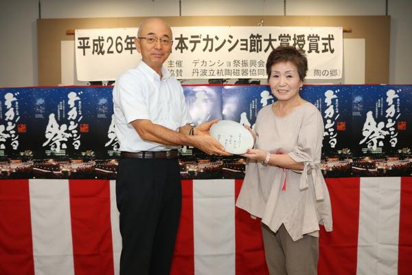日本デカンショ節優秀賞の村岡さんと市長がお祝い品を持ち記念写真