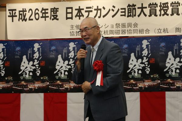 日本デカンショ節大賞の松葉さんがマイクで笑顔で挨拶をしている写真