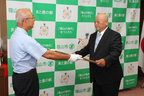 市長が井関 道夫さんへ紺綬褒章を渡している写真