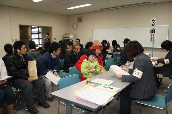 配布説明会に来られたが順番を待ち、篠山市の職員が親子に受付をしている写真