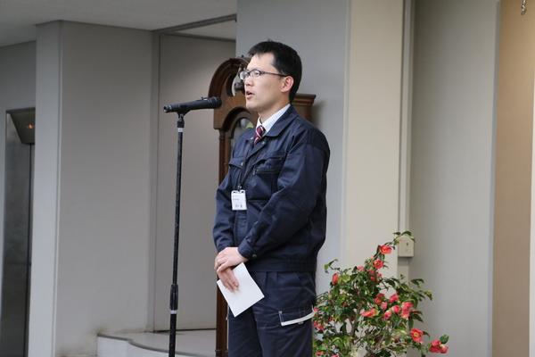 田中 健さんがスタンドマイクで挨拶をしている写真