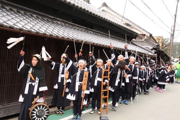 黒の衣装を着た子ども義士行列で「エイエイオー！」と大きな声を張り上げている子供たちの写真