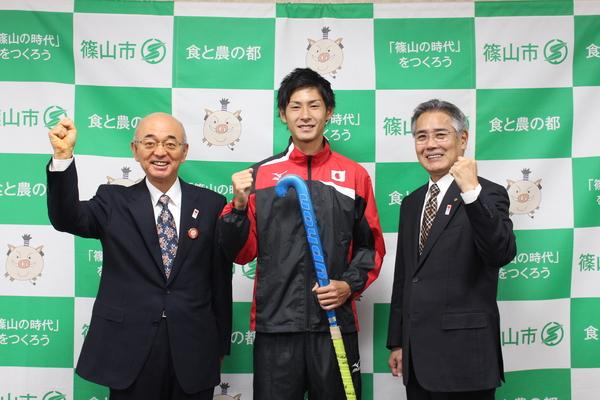 稲山 巧選手と市長と関係者の方がガッツポーズをしている写真