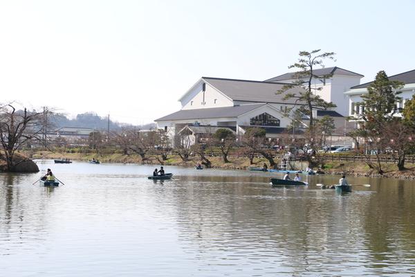 お掘りにボートを楽しむ方がいて後ろに篠山市役所が見えている写真