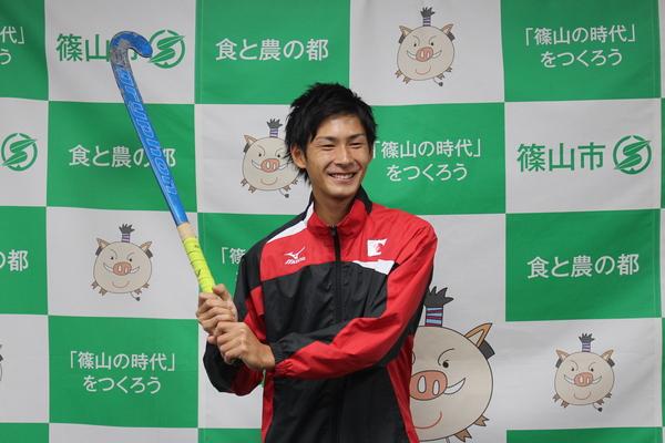 笑顔でホッケースティックを持っている稲山 巧選手の写真