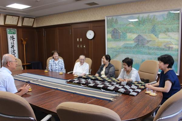 寄贈くださった座布団を机に置き通所介護施設「風和」の皆さんと市長が談笑している写真
