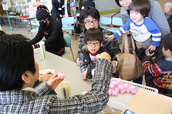 職員がピンクの容器に入ったヨウ素剤を、家族に渡している写真