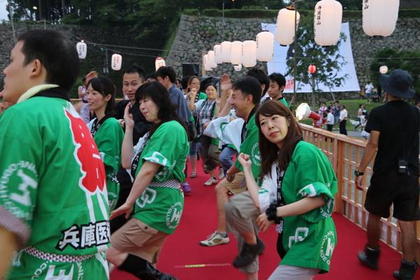 緑の法被を着て踊る男女の写真