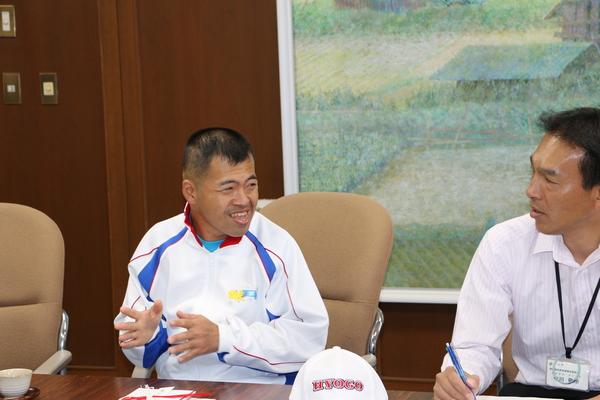 ジャージ姿の、岡 淳司（おか じゅんじ）さんと関係者が会話をしている写真