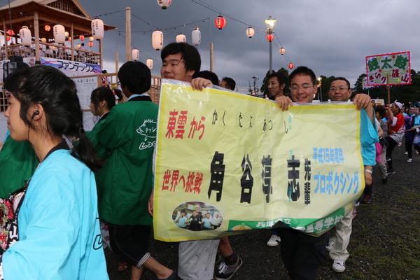 プロボクシング、角谷 淳志先輩と書かれた紙を持って歩く男性2名の写真