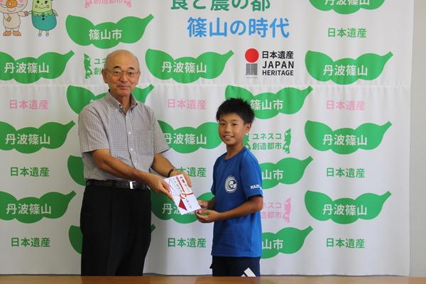 市長がホッケーチームの生徒に祝い金を渡している写真